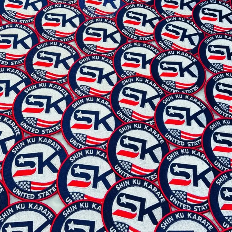 Large bulk production order of custom embroidered Shin Ku Karate patches arranged in neat rows.