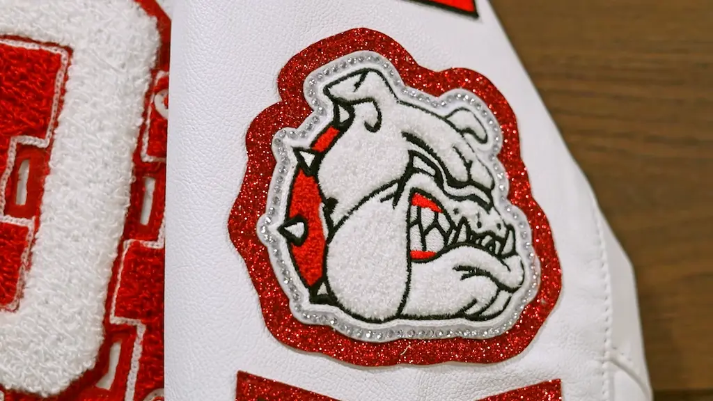 Close-up of chenille bulldog patch stitched on varsity jacket with raised texture and glitter border