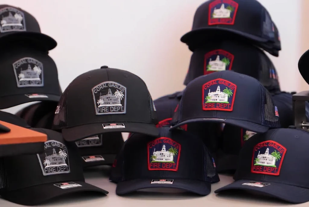 Collection of black and navy trucker hats with embroidered Coral Gables Fire Dept patches