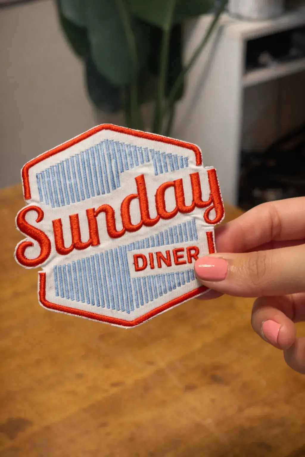 Hand holding custom embroidered Sunday Diner logo patch