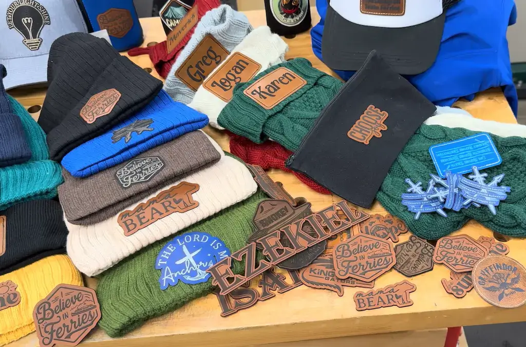 Display of custom leather patches applied to beanies, hats, and accessories showing embossed branding and personalized designs