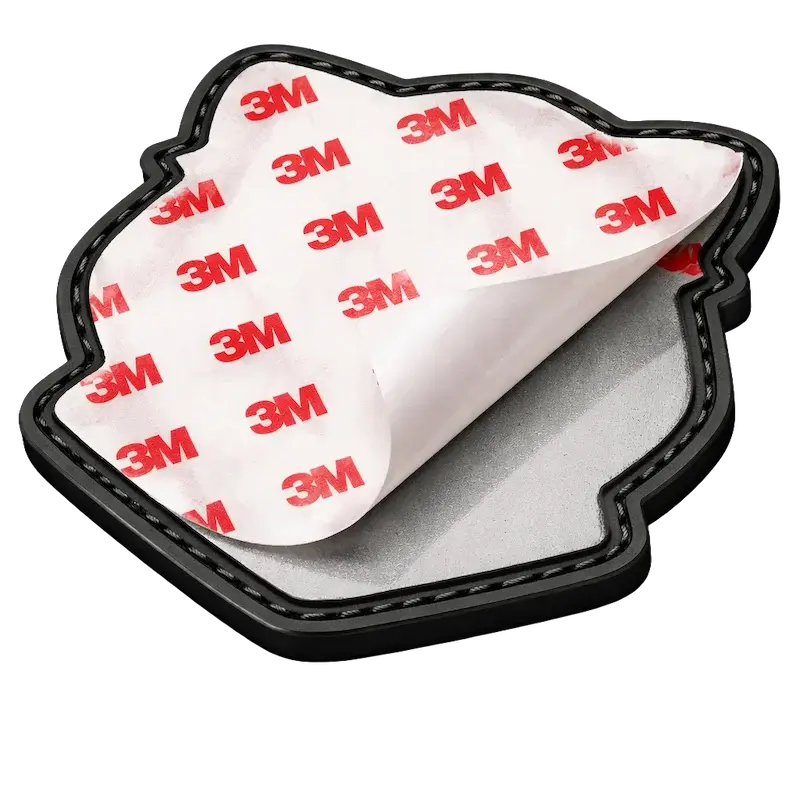 Close-up of PVC patch back showing 3M adhesive peel-and-stick backing with red logo liner for temporary application.