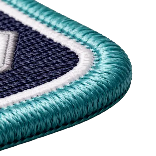 Macro detail of a traditional merrowed border with thick teal thread wrapped around the edge of an embroidered patch.