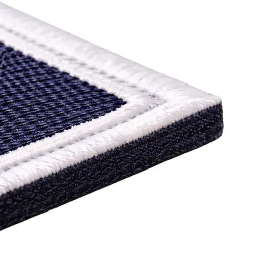 Extreme macro photography of a laser-cut embroidered patch edge showing a precise heat-sealed flat profile on dark twill.